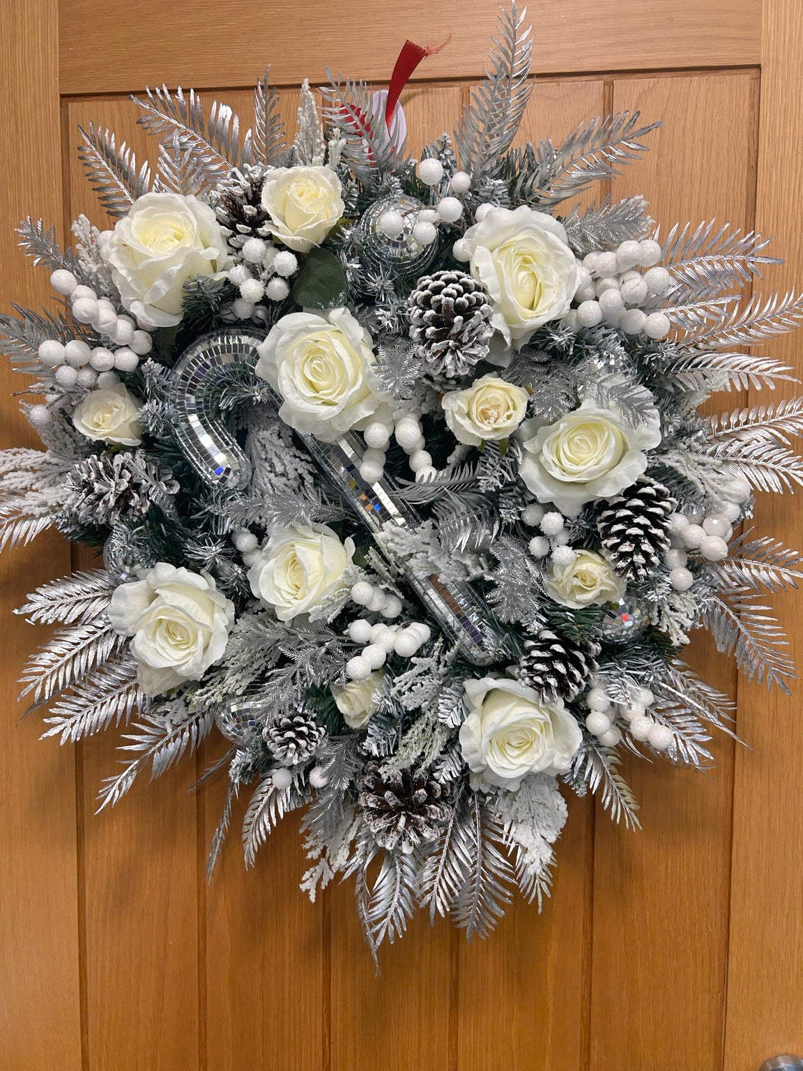 Silver and white Christmas wreath with ivory roses, frosted pinecones, white berries and mirrored decorations